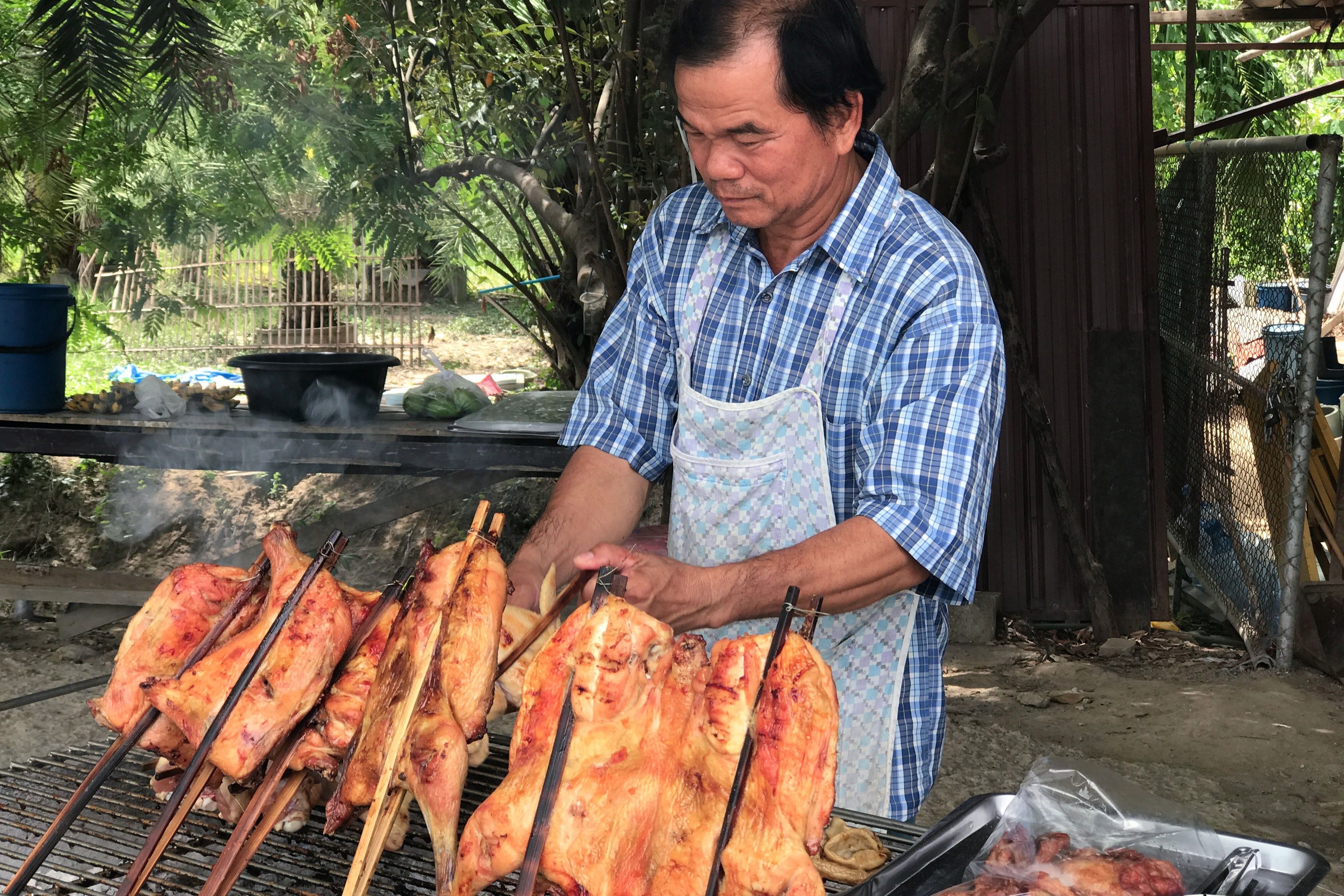 A cook turning chickens on a grill