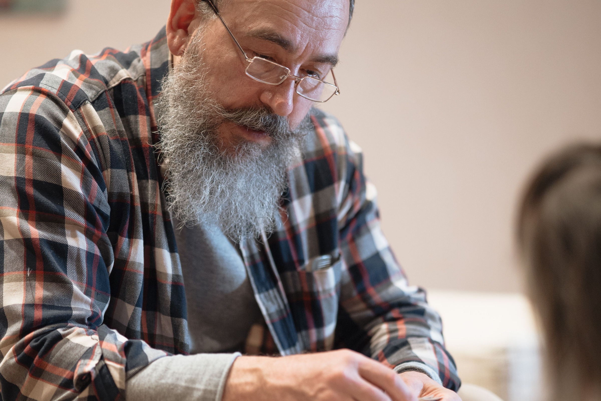A man with glasses sitting quietly, looking down