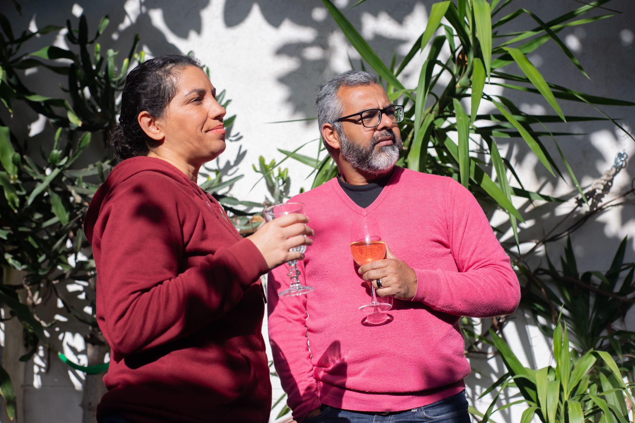 Two people sharing a drink on a plant-filled patio